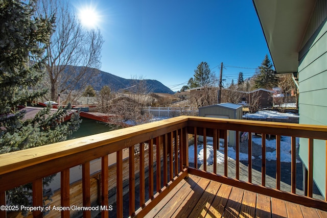 wooden terrace featuring a storage shed, an outdoor structure, fence, and a mountain view