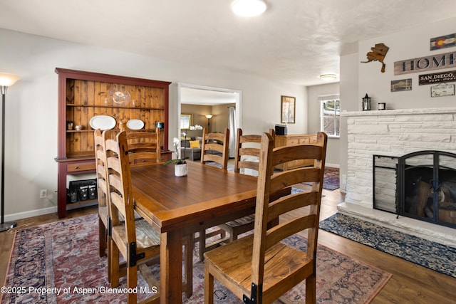 dining space with a fireplace, wood finished floors, and baseboards