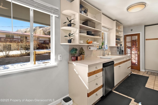 kitchen featuring light tile patterned floors, open shelves, light countertops, a sink, and dishwasher