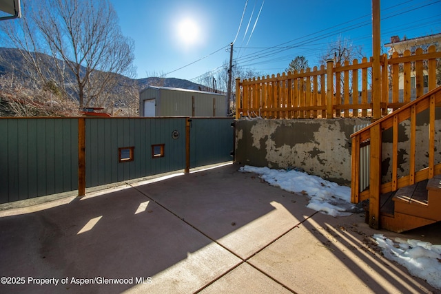 view of patio / terrace featuring fence, an outdoor structure, and a mountain view