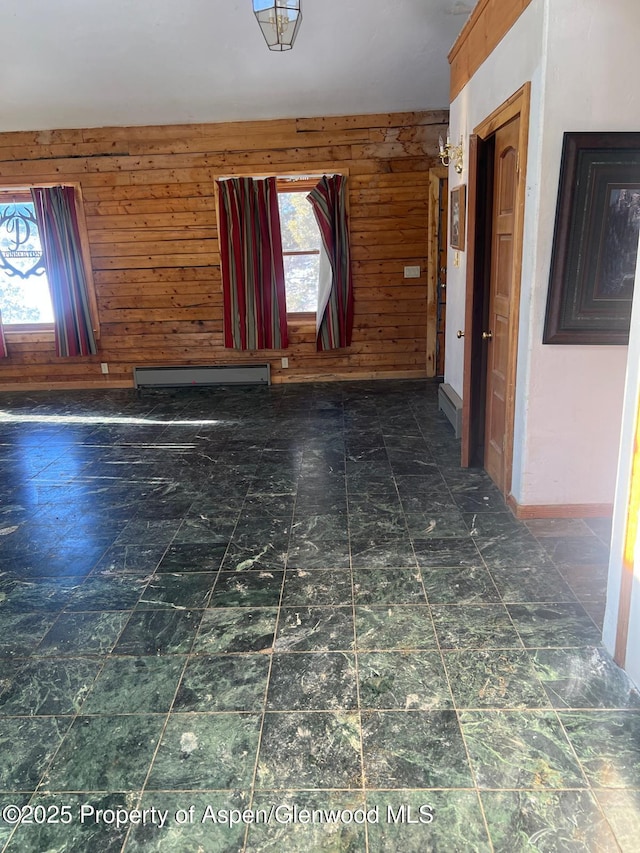 empty room with a baseboard heating unit, a wealth of natural light, and wooden walls