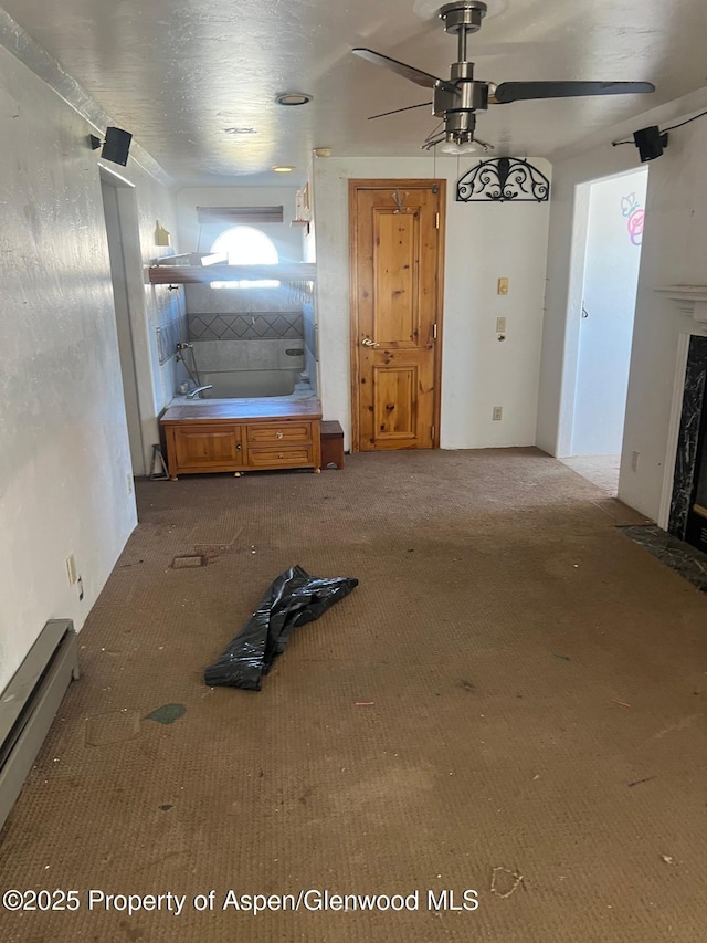 interior space featuring carpet floors, a baseboard heating unit, ceiling fan, and a fireplace