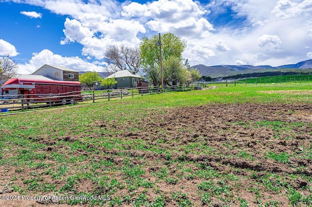 view of yard featuring a mountain view, an outbuilding, and a rural view