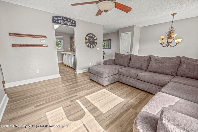 830 Exmoor Rd, Craig, CO 81625 - living area featuring a ceiling fan, light wood-type flooring, a chandelier, a textured ceiling, and baseboards