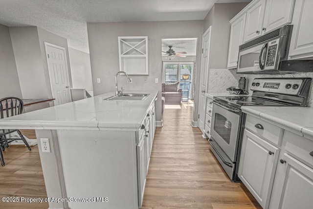 830 Exmoor Rd, Craig, CO 81625 - kitchen with stainless steel range with electric stovetop, a sink, black microwave, light wood finished floors, and a ceiling fan