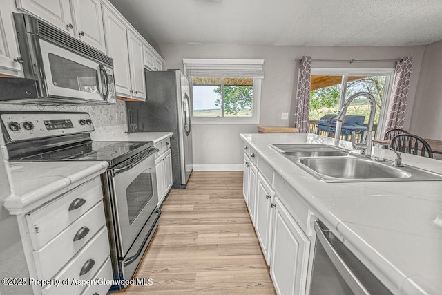 830 Exmoor Rd, Craig, CO 81625 - kitchen with stainless steel appliances, a sink, light wood-style flooring, baseboards, and white cabinets