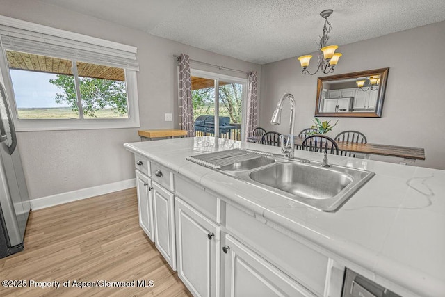 830 Exmoor Rd, Craig, CO 81625 - kitchen featuring a sink, baseboards, a chandelier, white cabinets, and light wood-type flooring
