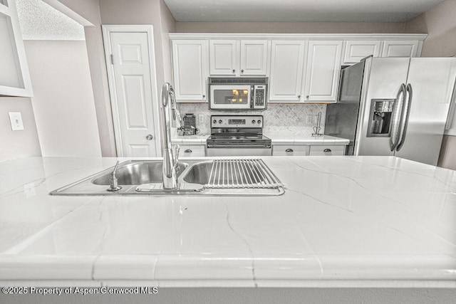 830 Exmoor Rd, Craig, CO 81625 - kitchen featuring stainless steel appliances, white cabinets, light stone counters, and decorative backsplash