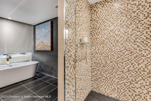 bathroom with a bathtub, tile patterned floors, and tile walls