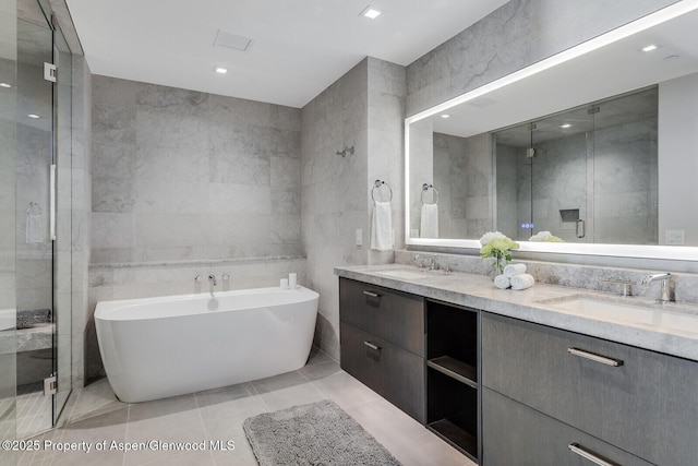full bathroom featuring a shower stall, double vanity, tile walls, and a sink