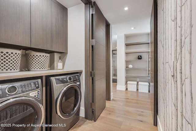 washroom with light wood-style flooring, washing machine and clothes dryer, and cabinet space