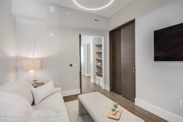 living room featuring visible vents, baseboards, and wood finished floors
