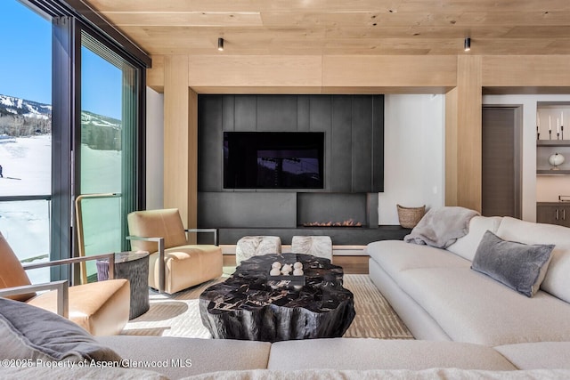 living area with wooden ceiling, a baseboard heating unit, wood finished floors, and expansive windows