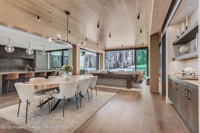 dining room featuring light wood-type flooring and wooden ceiling