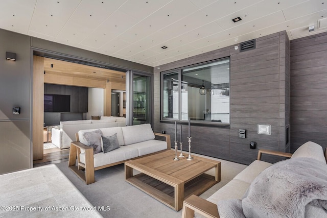 living area with wooden walls and visible vents