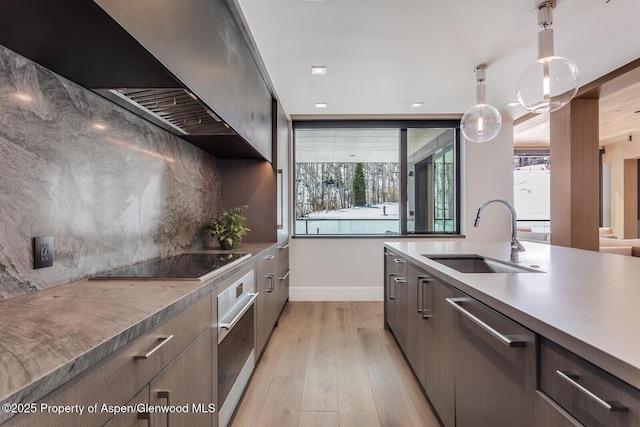 kitchen with modern cabinets, a wealth of natural light, a sink, stainless steel appliances, and baseboards