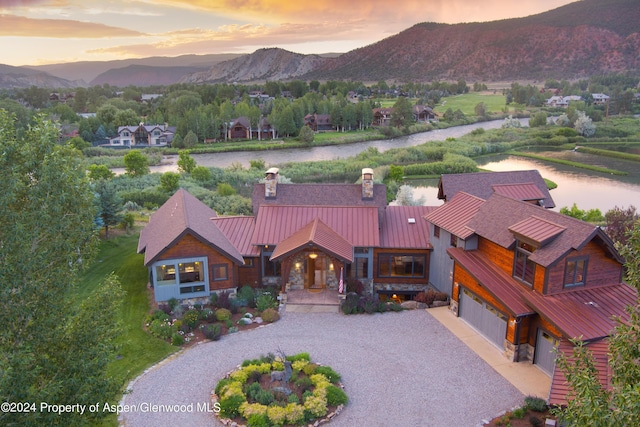 aerial view at dusk featuring a water and mountain view