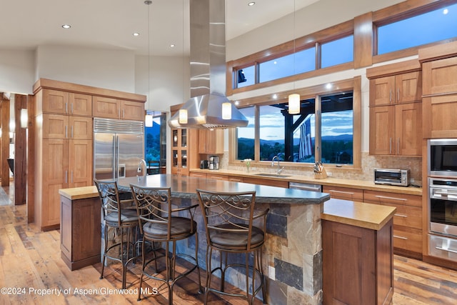 kitchen featuring built in appliances, a center island, sink, and hanging light fixtures