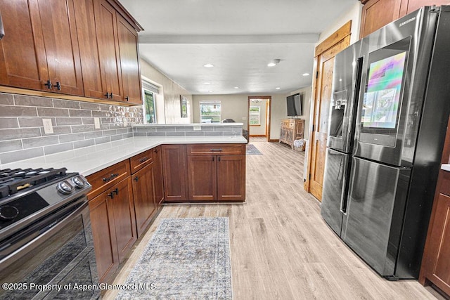 949 Breeze St, Craig, CO 81625 - kitchen featuring stainless steel fridge with ice dispenser, gas stove, a peninsula, light wood-type flooring, and decorative backsplash