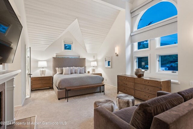 bedroom featuring beam ceiling, light colored carpet, a fireplace, and high vaulted ceiling