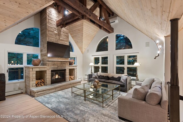 living room featuring light wood-type flooring, wood ceiling, baseboard heating, high vaulted ceiling, and a stone fireplace