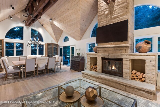 living room featuring wooden ceiling, high vaulted ceiling, light hardwood / wood-style flooring, a fireplace, and beamed ceiling