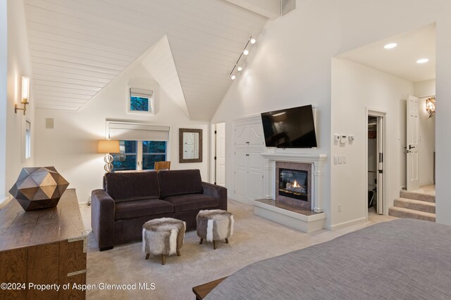 carpeted bedroom with vaulted ceiling with beams, rail lighting, and wood ceiling