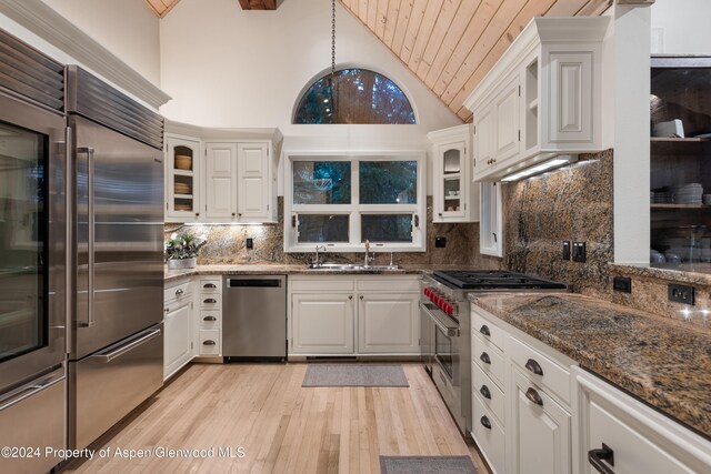 kitchen with high quality appliances, high vaulted ceiling, sink, decorative backsplash, and white cabinetry