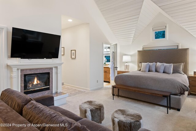 carpeted bedroom featuring ensuite bathroom, a premium fireplace, and vaulted ceiling