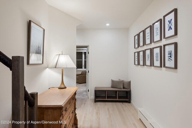 hallway with light hardwood / wood-style flooring and baseboard heating