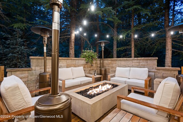 patio at night with an outdoor living space with a fire pit