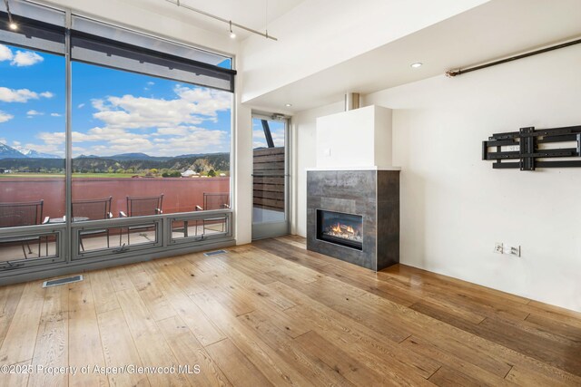 2635 Dolores Way, Carbondale, CO 81623 - living room featuring a tiled fireplace, track lighting, a mountain view, wood-type flooring, and visible vents