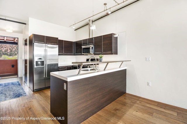 2635 Dolores Way, Carbondale, CO 81623 - kitchen featuring dark brown cabinetry, a peninsula, appliances with stainless steel finishes, and wood finished floors
