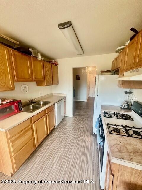 796 Castle Valley Blvd Unit J, New Castle, CO 81647 - kitchen with white appliances, under cabinet range hood, a sink, light countertops, and light wood-style floors