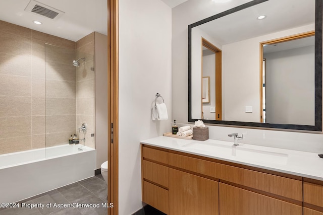 full bathroom with tiled shower / bath combo, vanity, tile patterned floors, and toilet