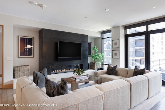 living room with expansive windows, a healthy amount of sunlight, a fireplace, and light hardwood / wood-style flooring