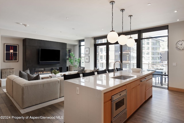 kitchen with pendant lighting, dark hardwood / wood-style floors, sink, and a kitchen island with sink