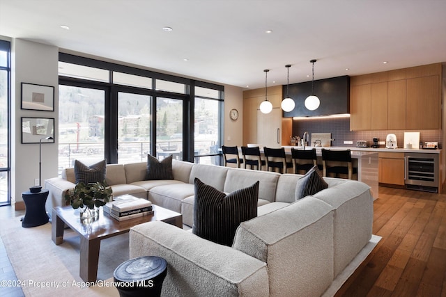 living room with expansive windows, beverage cooler, and light hardwood / wood-style flooring