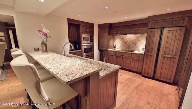 kitchen featuring a kitchen bar, appliances with stainless steel finishes, kitchen peninsula, and light hardwood / wood-style flooring