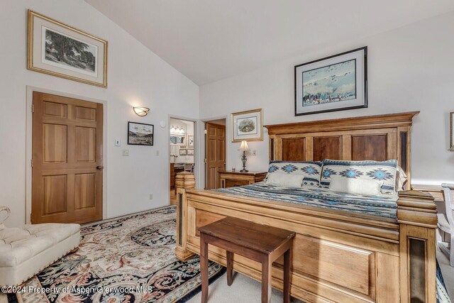 carpeted bedroom featuring connected bathroom and vaulted ceiling