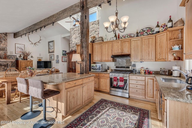 kitchen featuring sink, stainless steel appliances, light stone counters, beamed ceiling, and light wood-type flooring