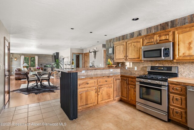1472 W Main St, Carbondale, CO 81623 - kitchen featuring stainless steel appliances, a peninsula, light tile patterned floors, open floor plan, and tasteful backsplash