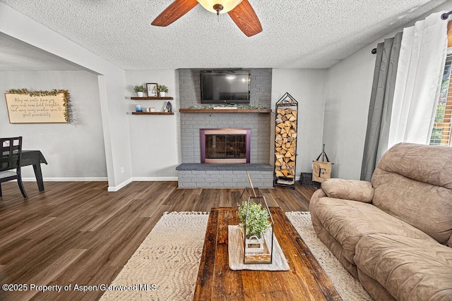 836 Ledford St, Craig, CO 81625 - living room with a textured ceiling, wood finished floors, a ceiling fan, a brick fireplace, and baseboards