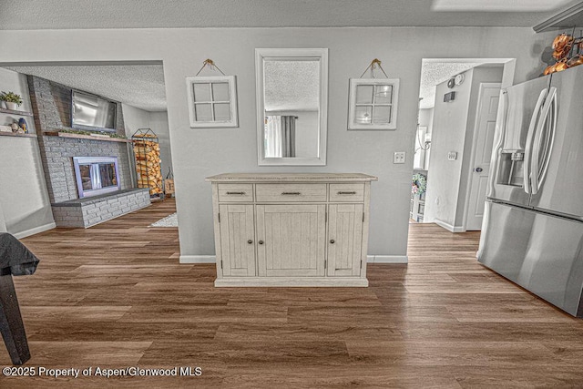 836 Ledford St, Craig, CO 81625 - kitchen featuring stainless steel refrigerator with ice dispenser, dark wood-style floors, a textured ceiling, a fireplace, and light countertops