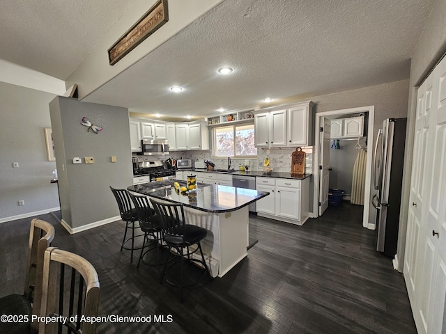 1650 Dogwood Dr, Rifle, CO 81650 - kitchen with stainless steel appliances, a sink, dark wood-type flooring, dark countertops, and a textured ceiling