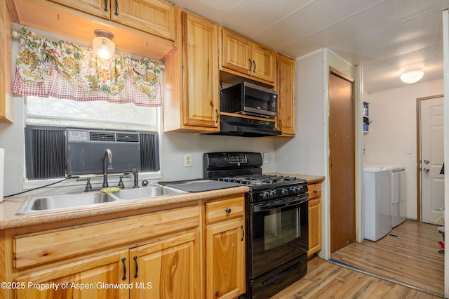 265 SW 11th Ave, Cedaredge, CO 81413 - kitchen featuring black range with gas stovetop, stainless steel microwave, washing machine and dryer, a sink, and light wood-style flooring