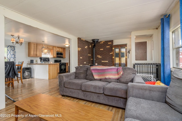 265 SW 11th Ave, Cedaredge, CO 81413 - living area with a wood stove, light wood-style floors, a chandelier, and brick wall