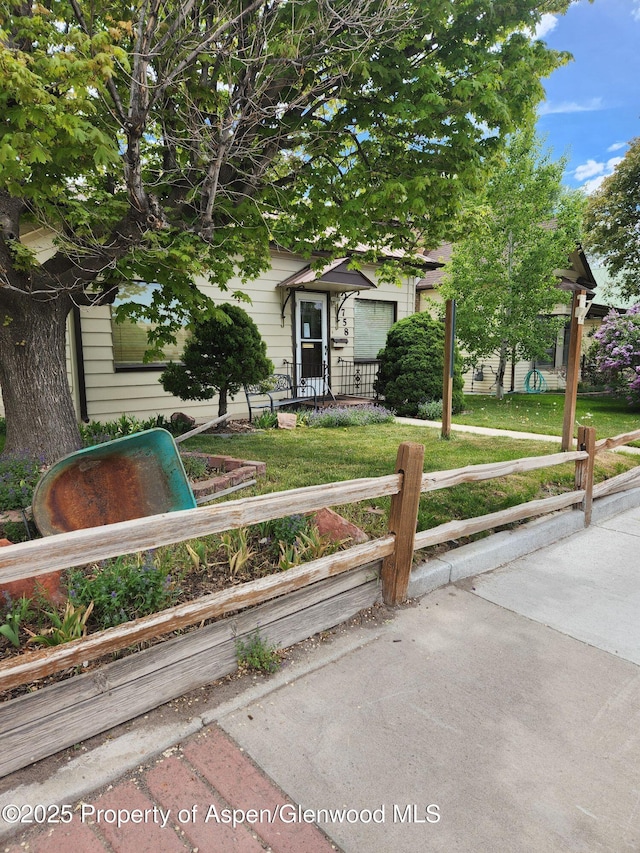 view of property hidden behind natural elements with a front yard