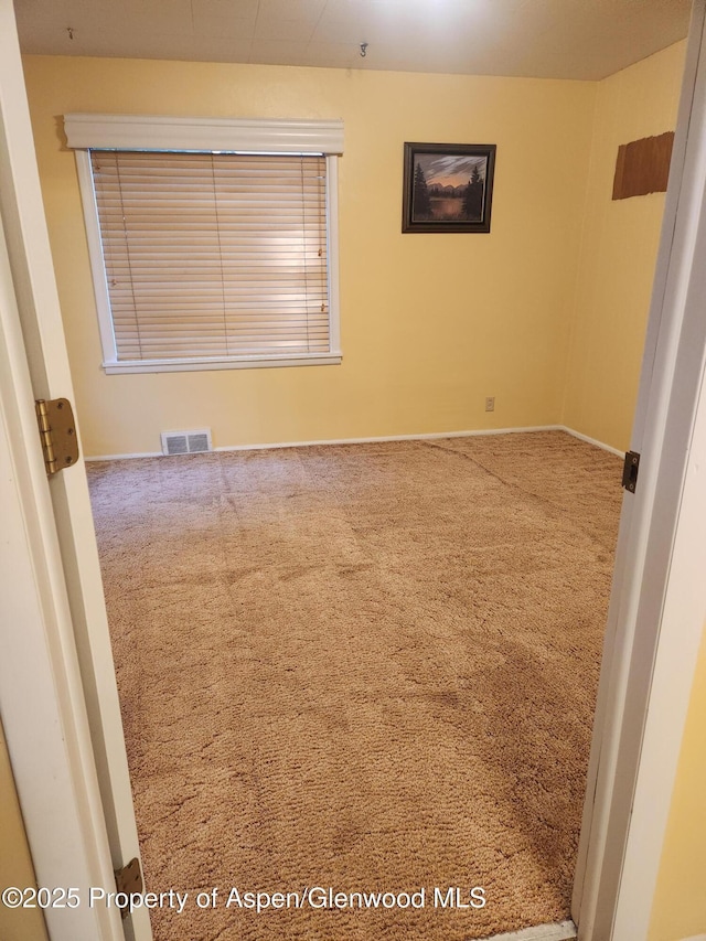 spare room featuring carpet flooring and baseboards
