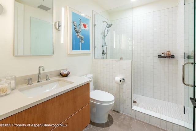 bathroom featuring vanity, tiled shower, tile patterned floors, and toilet